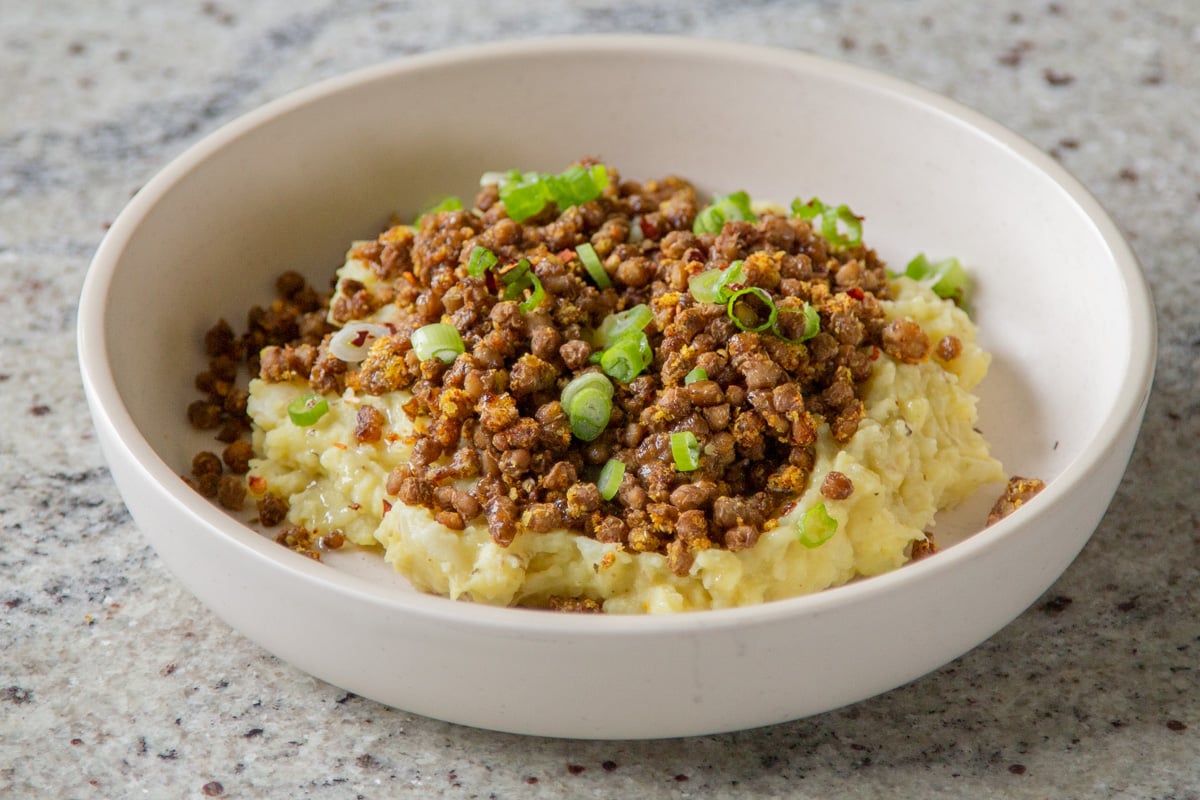 lentil mashed potatoes in a bowl with green onions on top