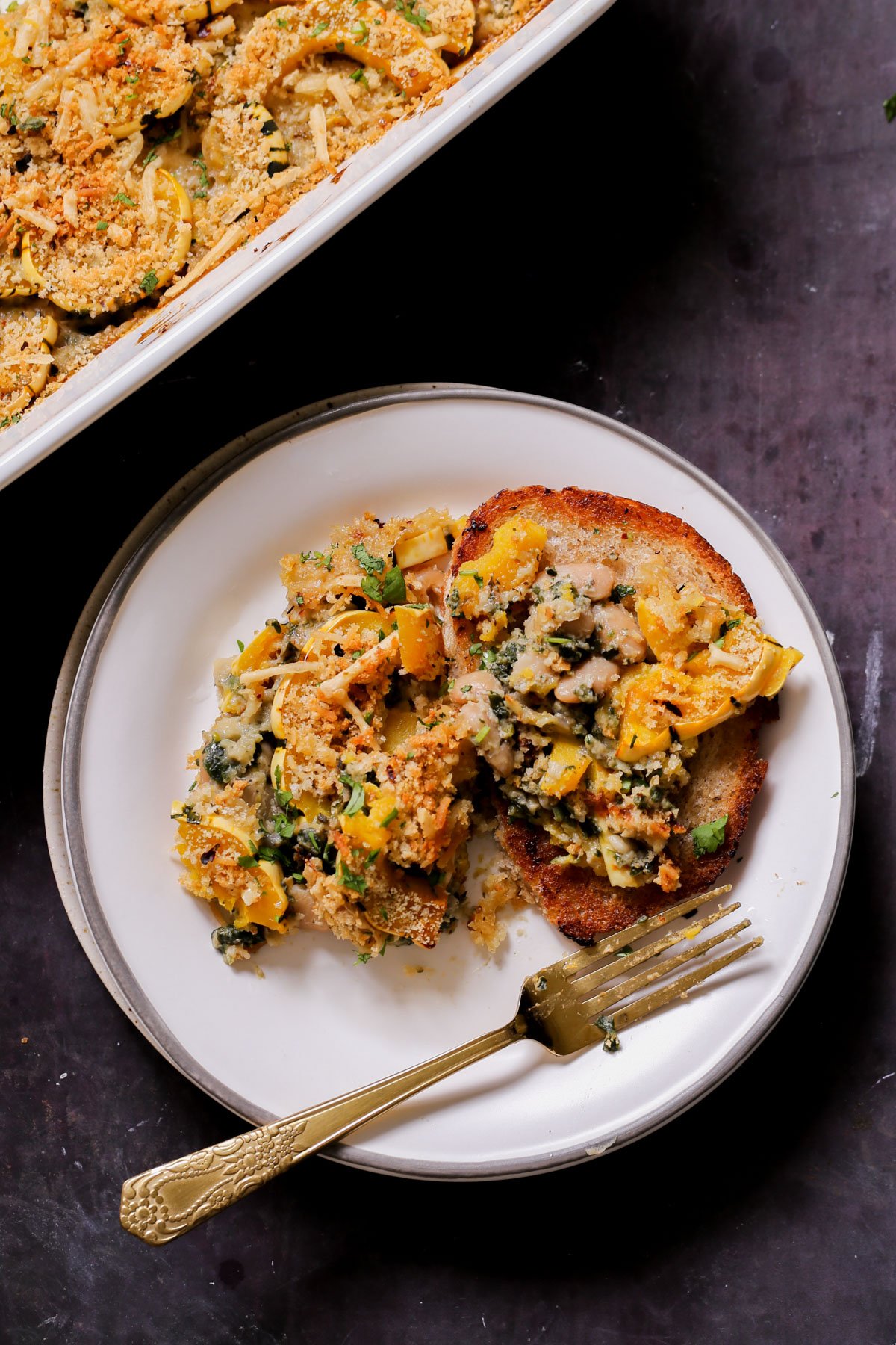 delicata squash casserole on a plate next to the casserole dish