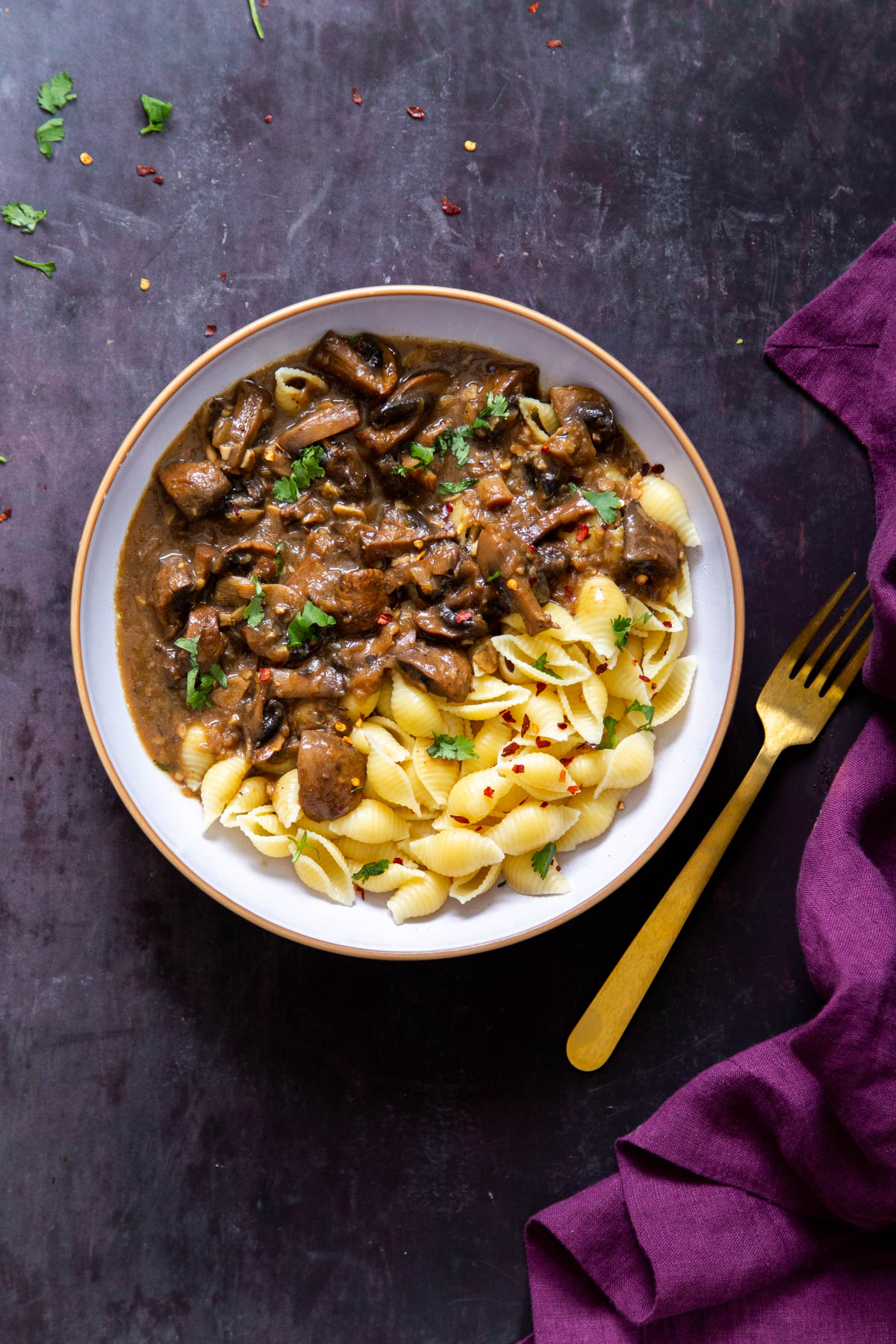 Instant Pot Garlic Mushrooms and shell pasta in a white bowl with a golden fork on the side