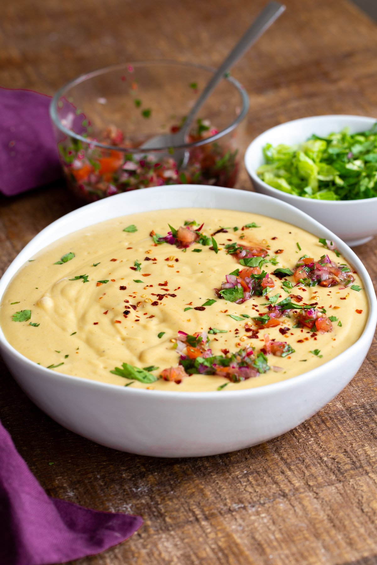 a bowl of vegan cheese sauce topped with pico de gallo and chopped cilantro