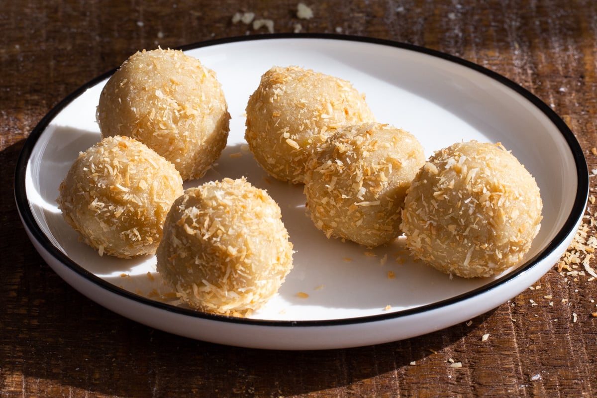 lemon coconut energy bites rolled in coconut on a small plate 